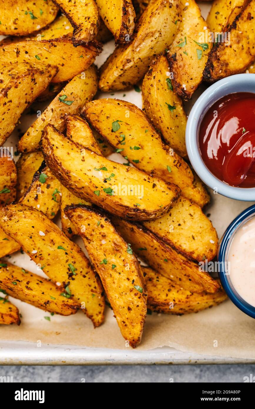 Foto über dem Kopf von Kartoffelkeilen in der würzigen Fritteuse Stockfoto