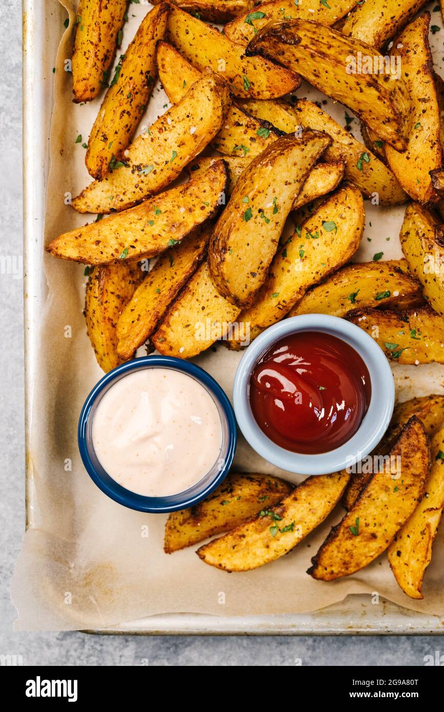 Foto über dem Kopf von Kartoffelkeilen in der würzigen Fritteuse Stockfoto