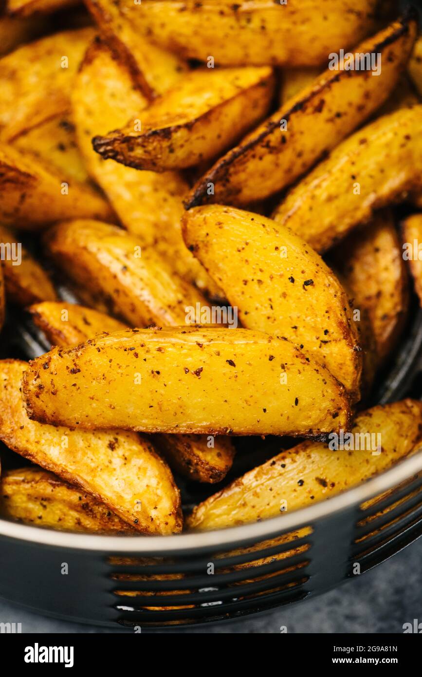 Würzige Kartoffelkeile in einem Korb mit Luftfryer Stockfoto