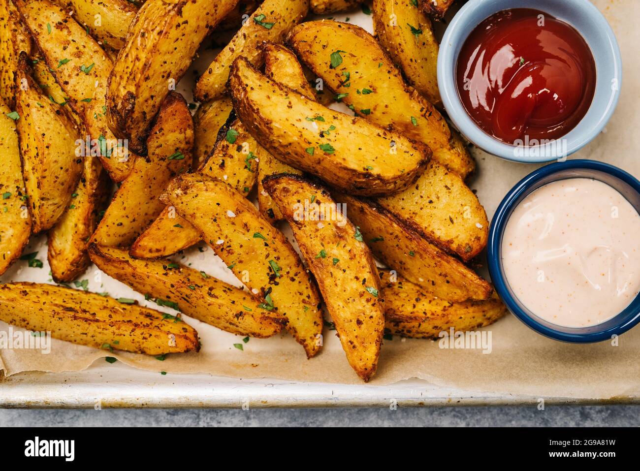 Foto über dem Kopf von Kartoffelkeilen mit Ketchup und Bratsoße Stockfoto