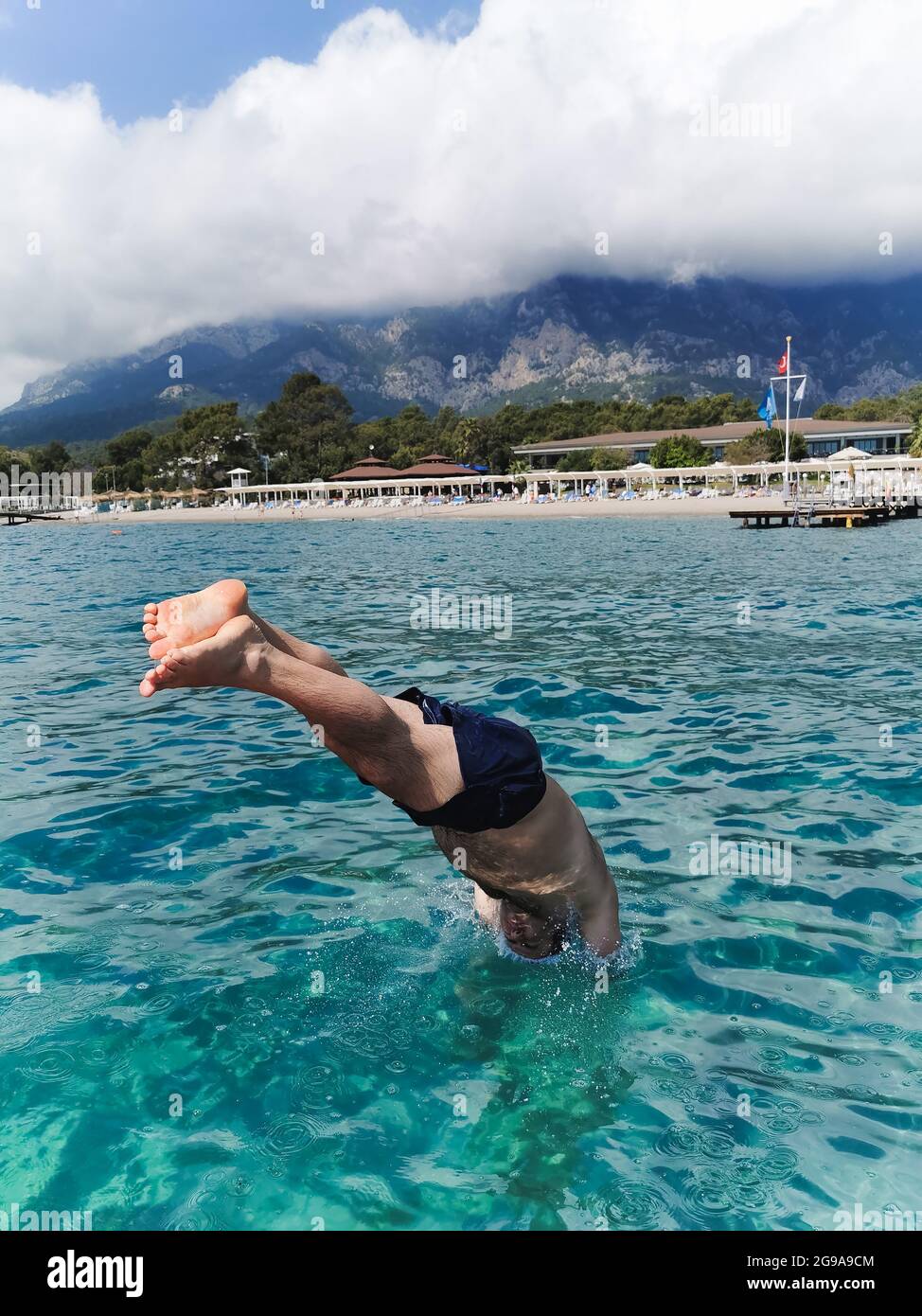Ein Mann taucht in Shorts von einer Plattform ins Meer Stockfoto