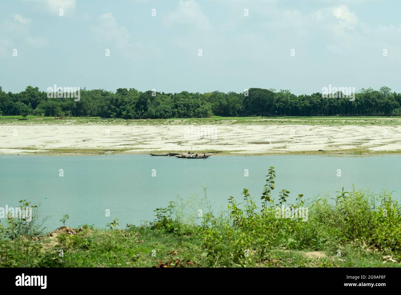 Der Gorai-Fluss mit blauem Wasser und umgeben von viel Grün, einige Boot schwimmt auf dem Wasser Fischer bereiten sich auf die Fischerei Stockfoto