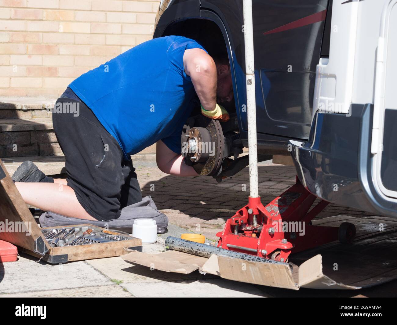 Ein Mechaniker hat ein Wohnmobil-Freizeitfahrzeug aufgebockt und ein Rad entfernt und unter dem Radlauf die Bremsen überprüft.Wagenheber Stockfoto