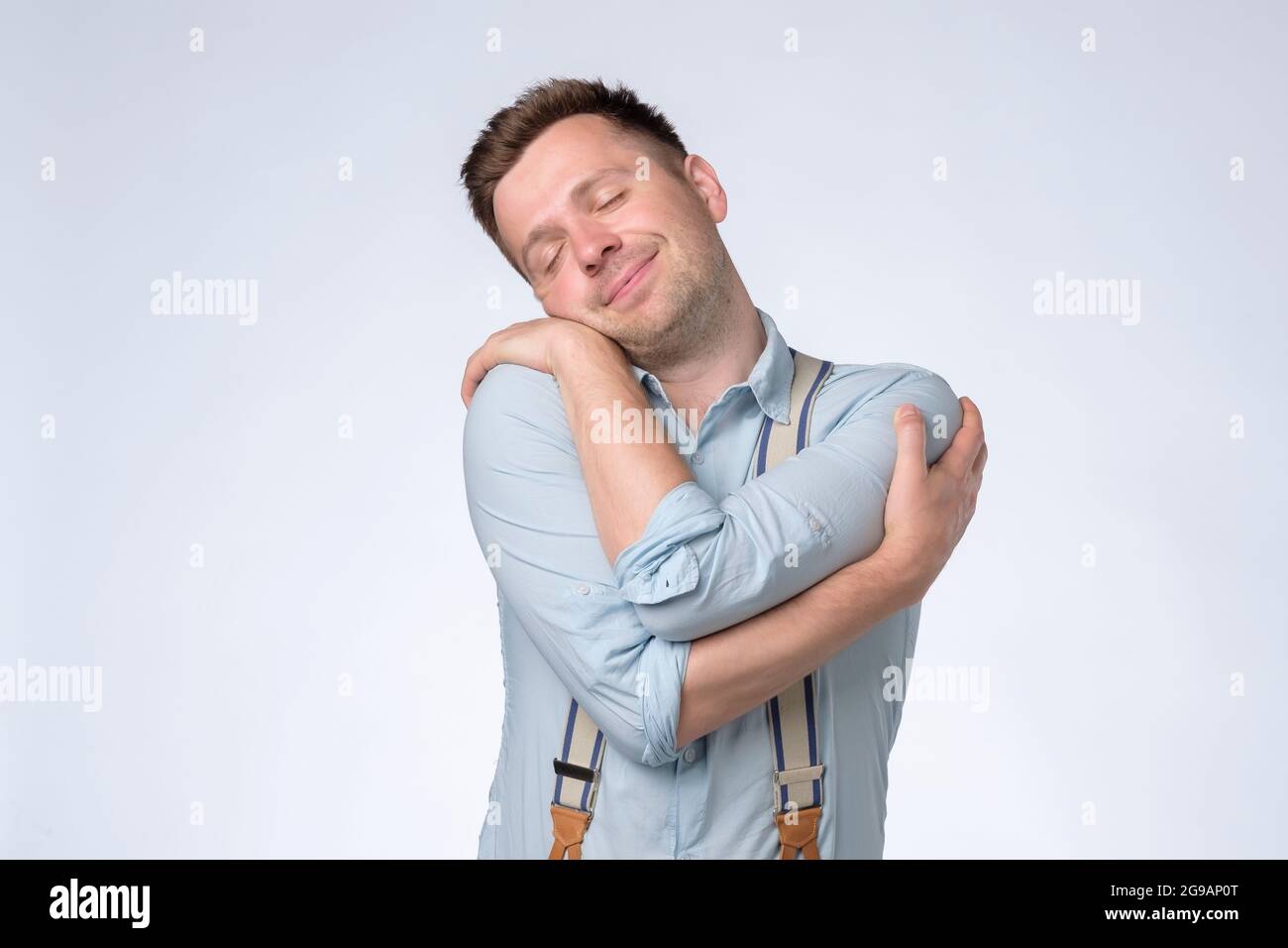 Erfreut kaukasischen Mann umarmt sich, hat ein hohes Selbstwertgefühl, fühlt sich wohl Stockfoto