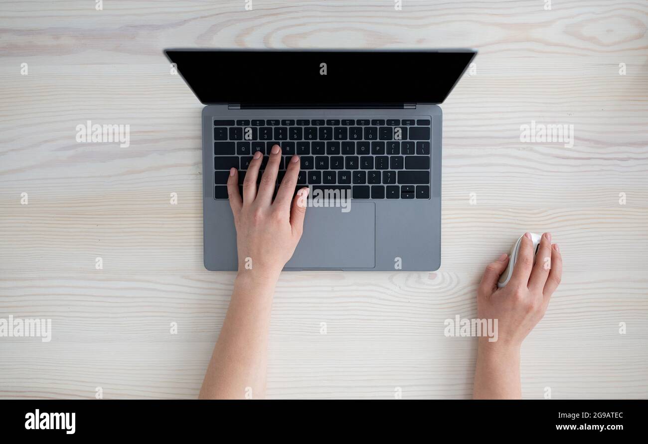 Technologiekonzept. Frau, die einen Laptop mit leerem Monitor benutzt, auf der Tastatur tippt und die Computermaus hält Stockfoto