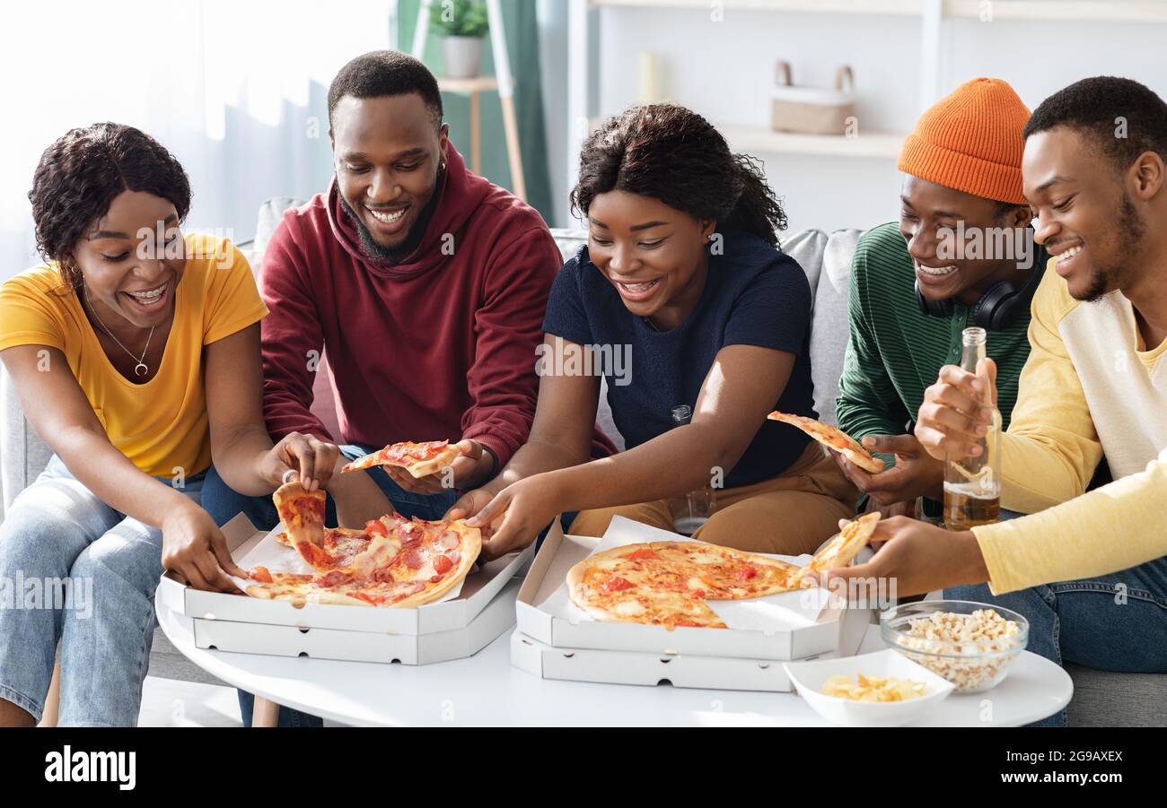 Positive schwarze Männer und Frauen essen Pizza zu Hause Stockfoto