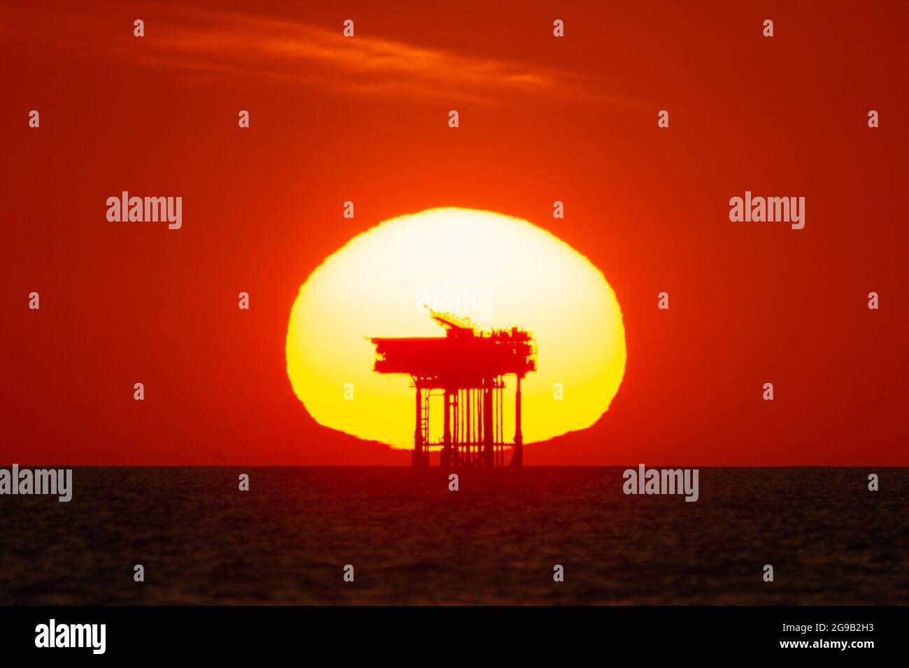 Blick auf den Sonnenuntergang hinter einer Offshore-Öl-/Gas-Plattform oder Bohrinsel auf See. Konzept oder Thema der fossilen Brennstoffe, Petrochemie, Sunset Industrie Stockfoto