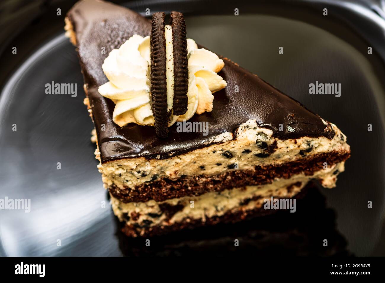 Ein hochgedrehter Schuss eines Schokoladenmousse-Kuchenstückes auf schwarzem Teller Stockfoto