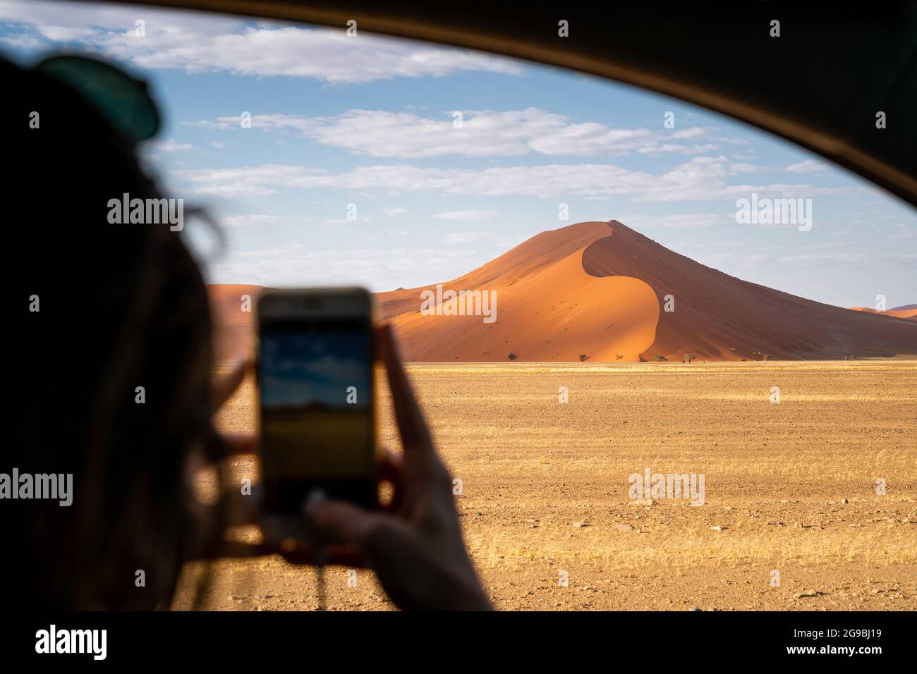 Tourist, der ein Handy-Foto von einer riesigen Sanddüne in der Nähe von Sossusvlei im Namib-Naukluft Nationalpark macht, Namibia, Afrika. Stockfoto