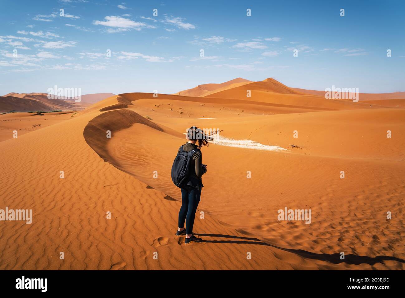 Aktive weibliche Reisende wandern auf den Dünen um Deadvlei in der Namib Wüste, Namib-Naukluft Nationalpark, Namibia, Afrika. Stockfoto