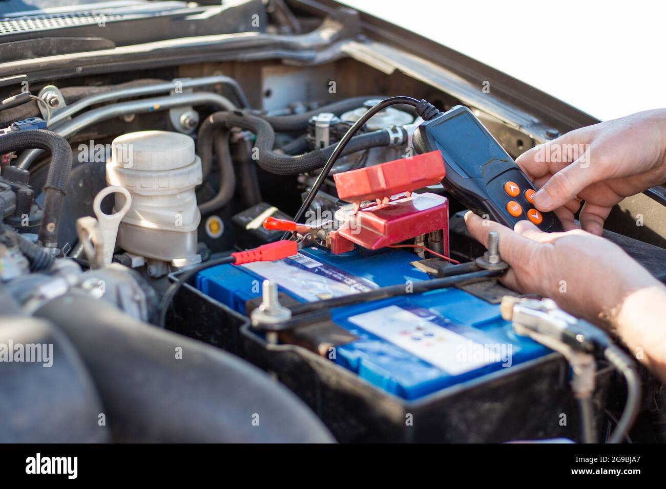 Ein Mann diagnostiziert eine Autobatterie mit einem Tester, Nahaufnahme. Reparatur und Austausch der Batterie. Stockfoto