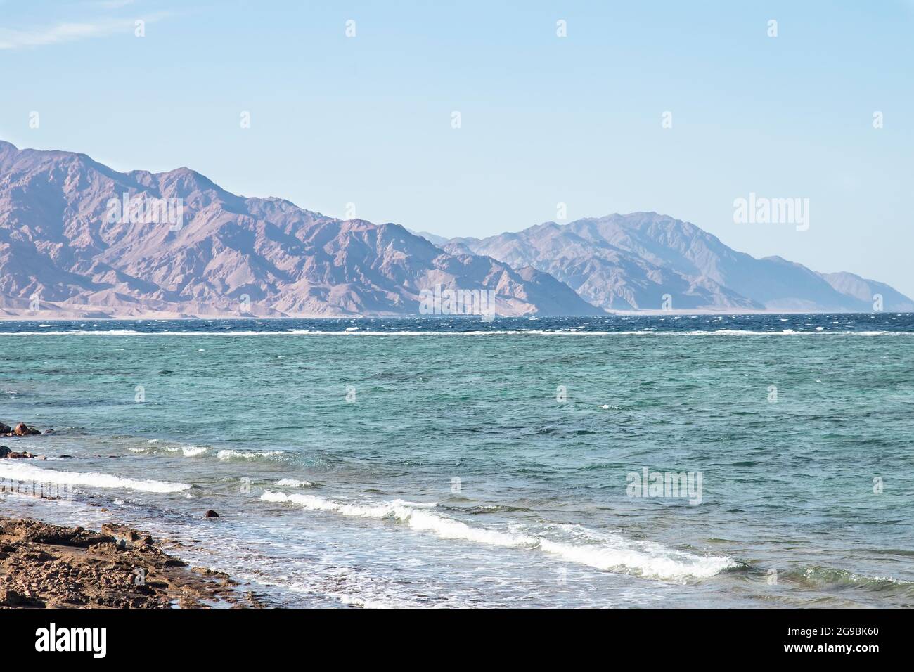 Sturm bei Sonnenuntergang und starker Wind mit Dunst über den Bergen. Landschaft mit stürmischem Meer und hohen Bergen am Ufer in Dahab. Reise zum Meer an Stockfoto