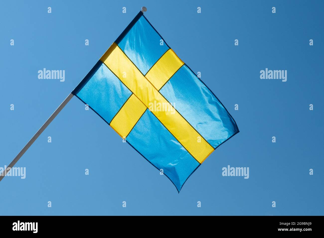Flagge Schwedens auf blauem Himmel Hintergrund. Schwedische Flagge winkt bei Wind und Sonnenlicht Stockfoto