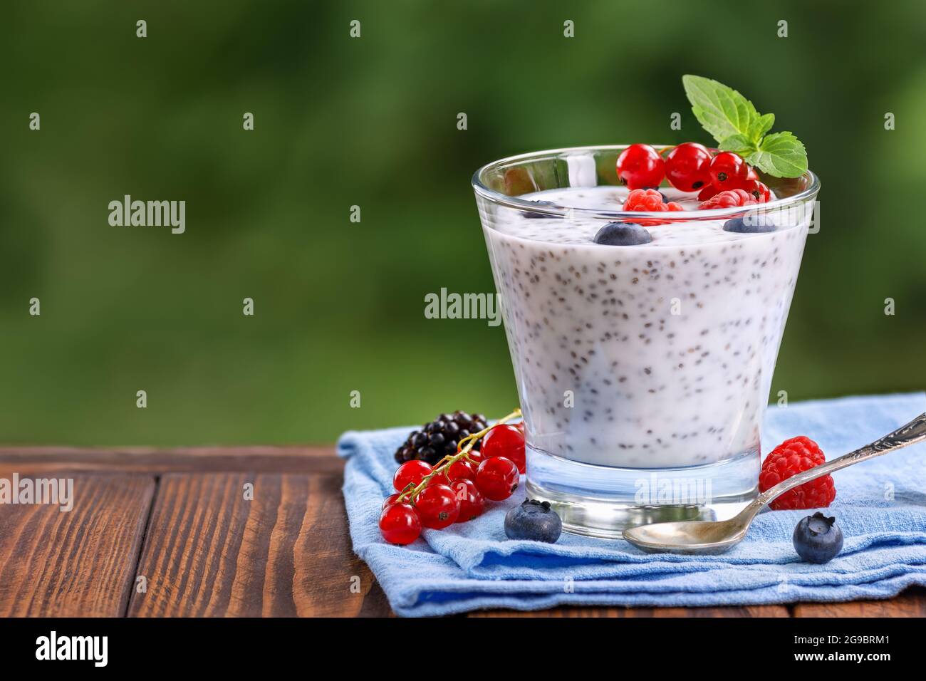 chia Pudding mit Joghurt und frischen Beeren im Glas auf dem Tisch im Freien Stockfoto
