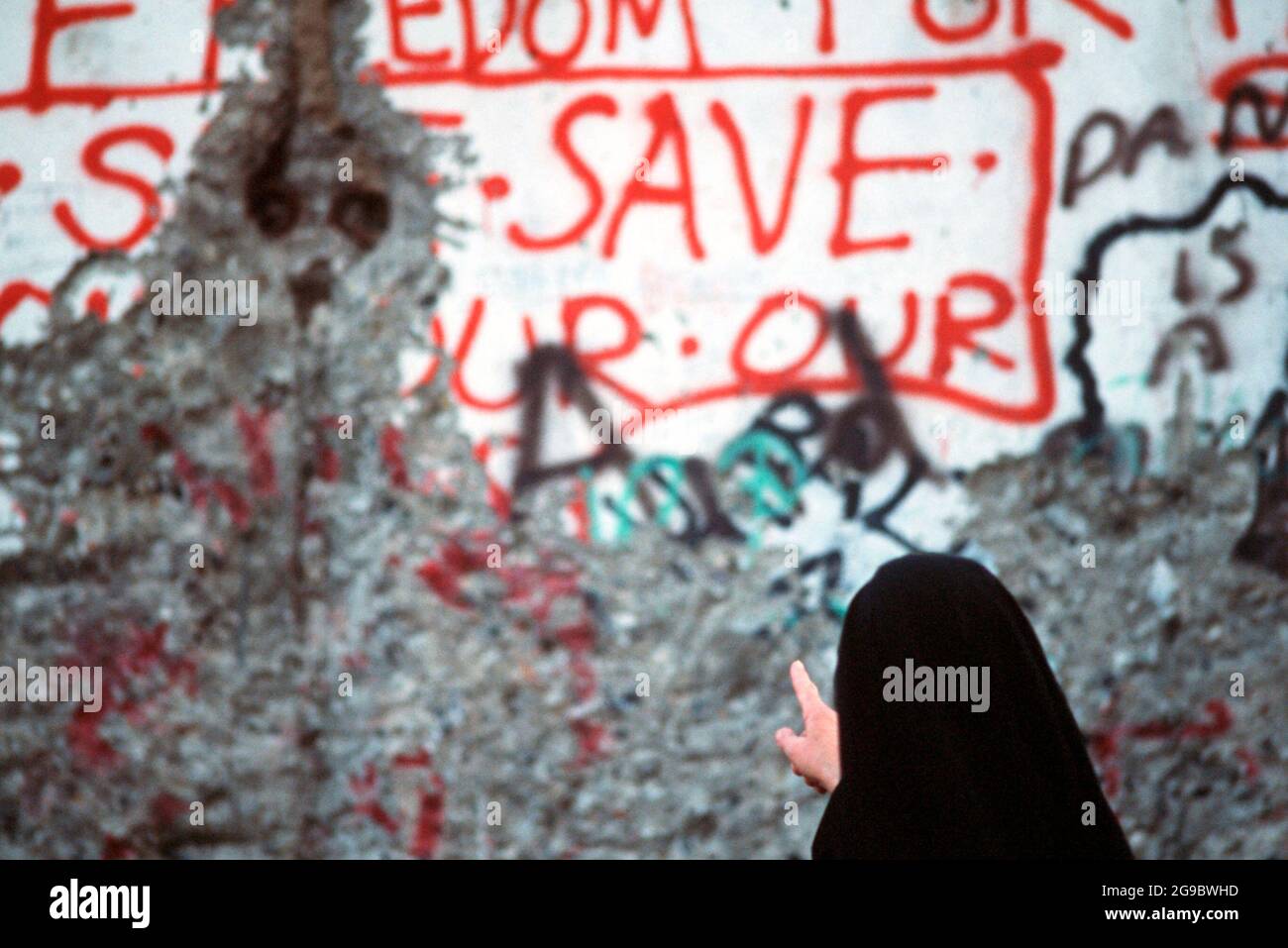 Eine Nonne studiert die Graffiti auf einem Abschnitt der Berliner Mauer, um 1989 Stockfoto