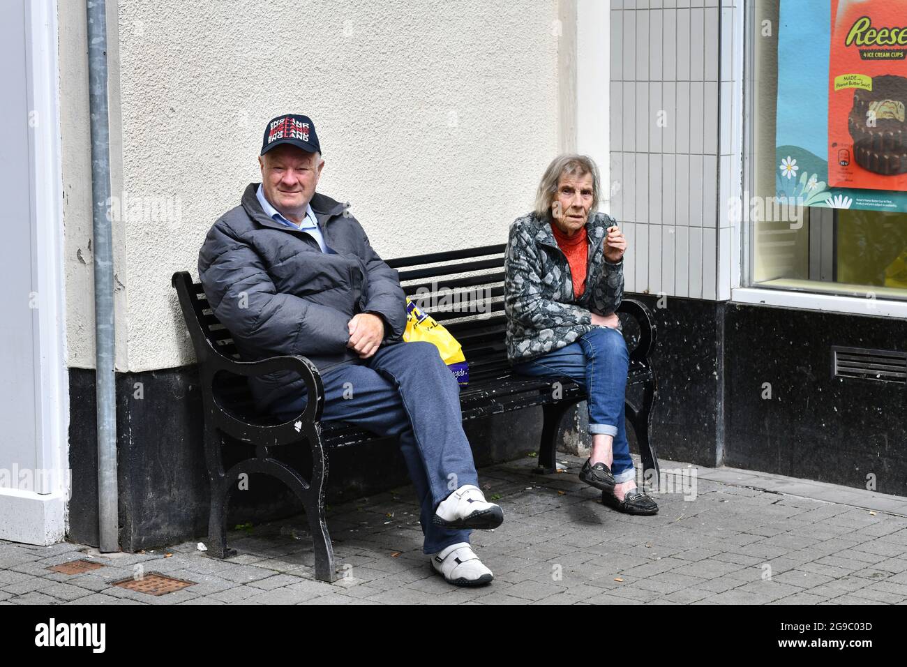 Ältere Dame, die beim Entspannen mit einer Zigarette Platz nimmt 2021. Straße Straßen Großbritannien Lifestyle Rauchen alte Sitzbank Stadtzentrum Großbritannien Stockfoto