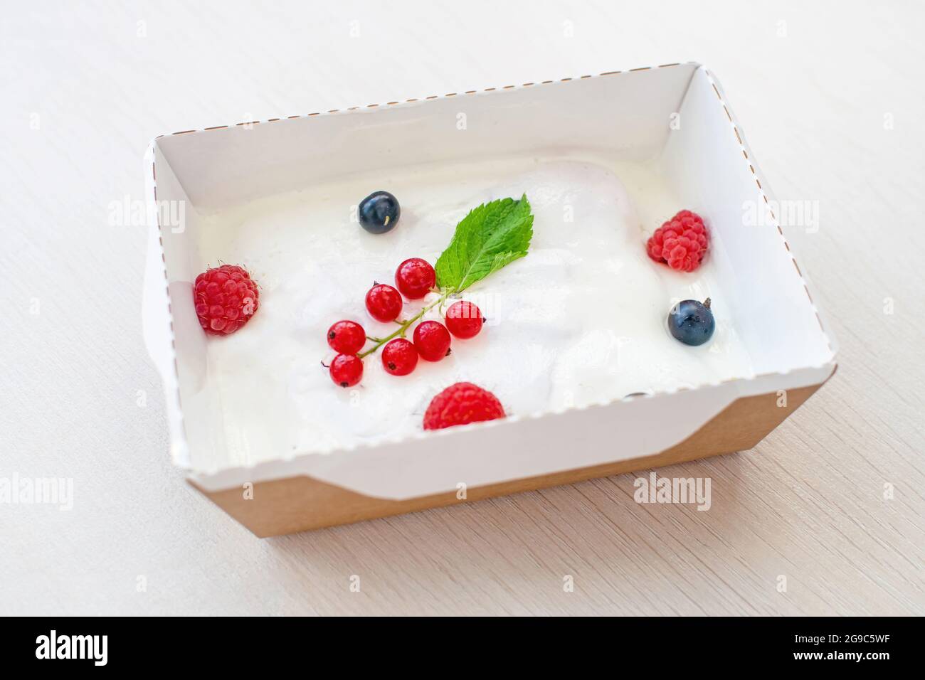 Ein erfrischendes Dessert aus Savoyardi, Grapefruitmarmelade und Sauerrahm mit Himbeeren und Johannisbeeren. Stockfoto