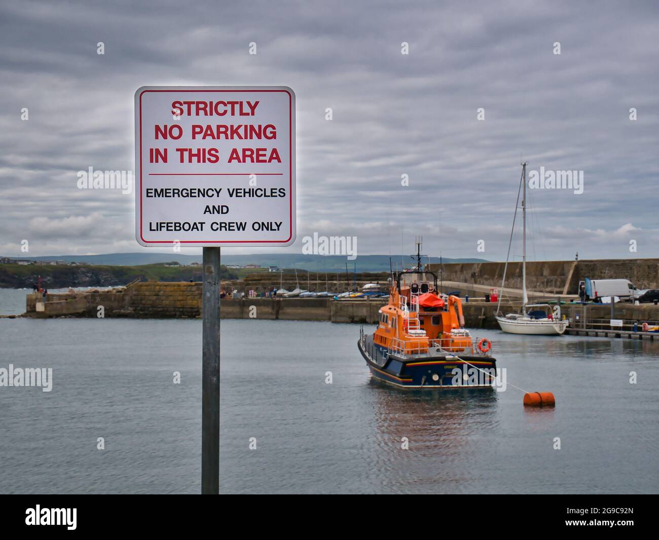 Im nordirischen Portrush Harbour steht auf einem Schild mit rotem Text auf weißem Hintergrund, dass außer Notfahrzeugen kein Parken erlaubt ist Stockfoto