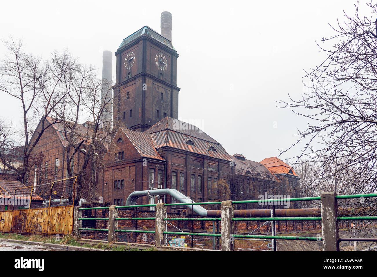 Altes Kohlekraftwerk im Bezirk Szombierki in Bytom, Schlesien, Polen. Industrie-, Backsteingebäude mit Uhrturm und Kaminen an einem nebligen Tag. Stockfoto