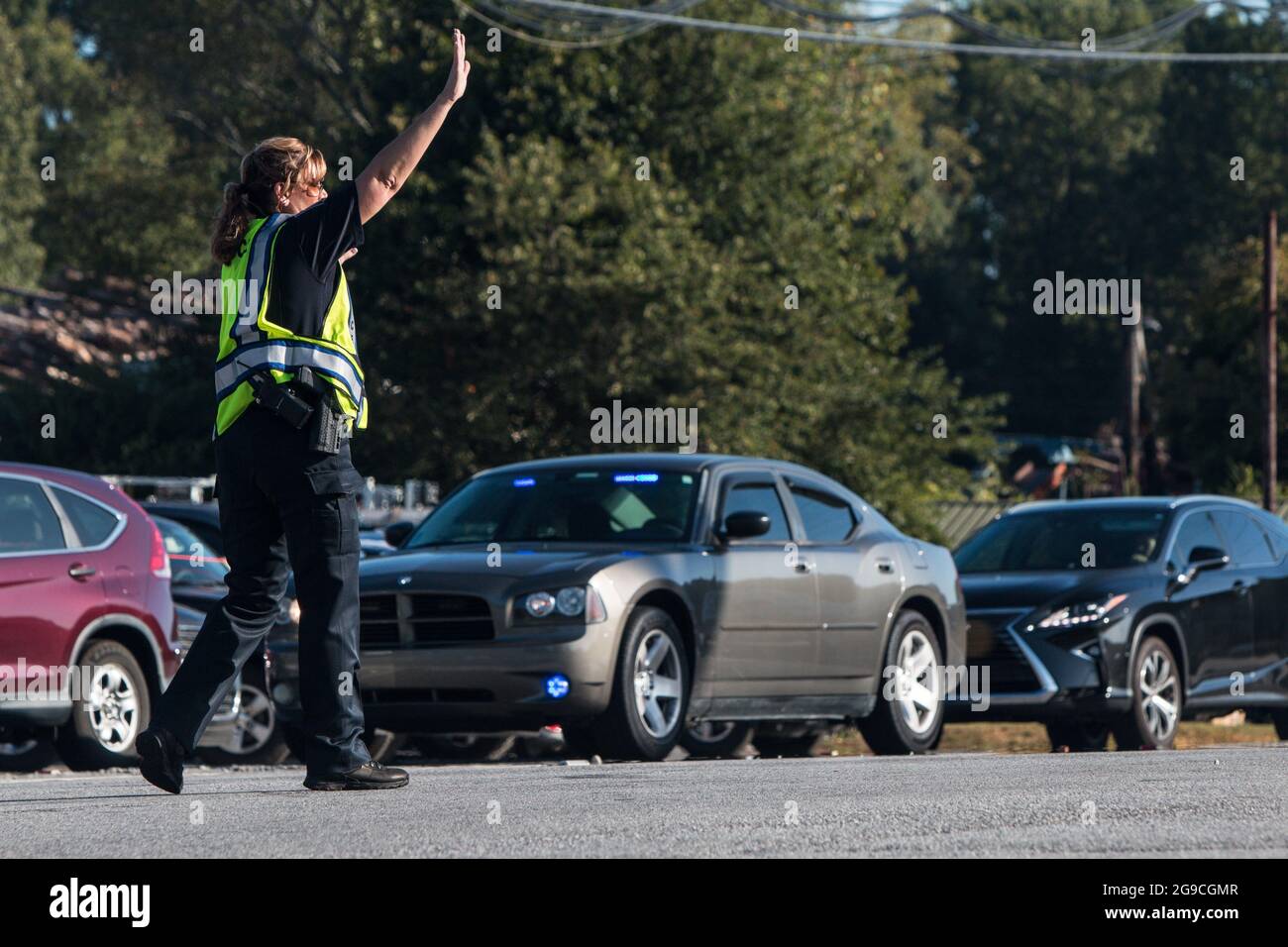 Suwanee, GA, USA - 21. September 2019: Eine Polizistin legt ihre Hand hoch, um den Verkehr zu stoppen, während sie den Fahrzeugverkehr auf einem Herbstfest leitet. Stockfoto