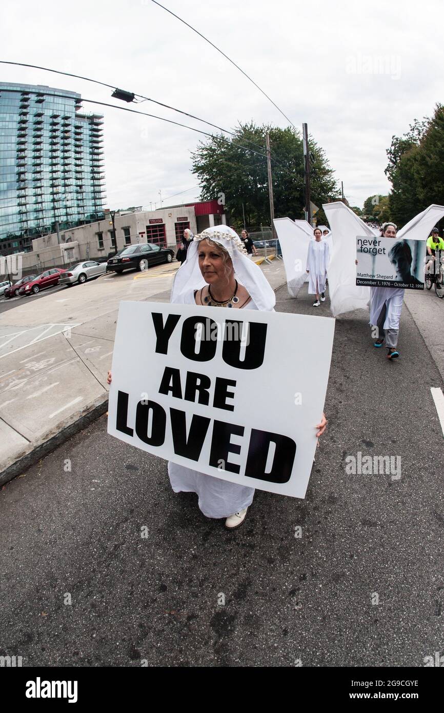 Atlanta, GA, USA - 12. Oktober 2019: Eine als Engel gekleidete Frau trägt ein Schild mit der Aufschrift „You are loved“ bei der Transgender-Parade in Atlanta. Stockfoto