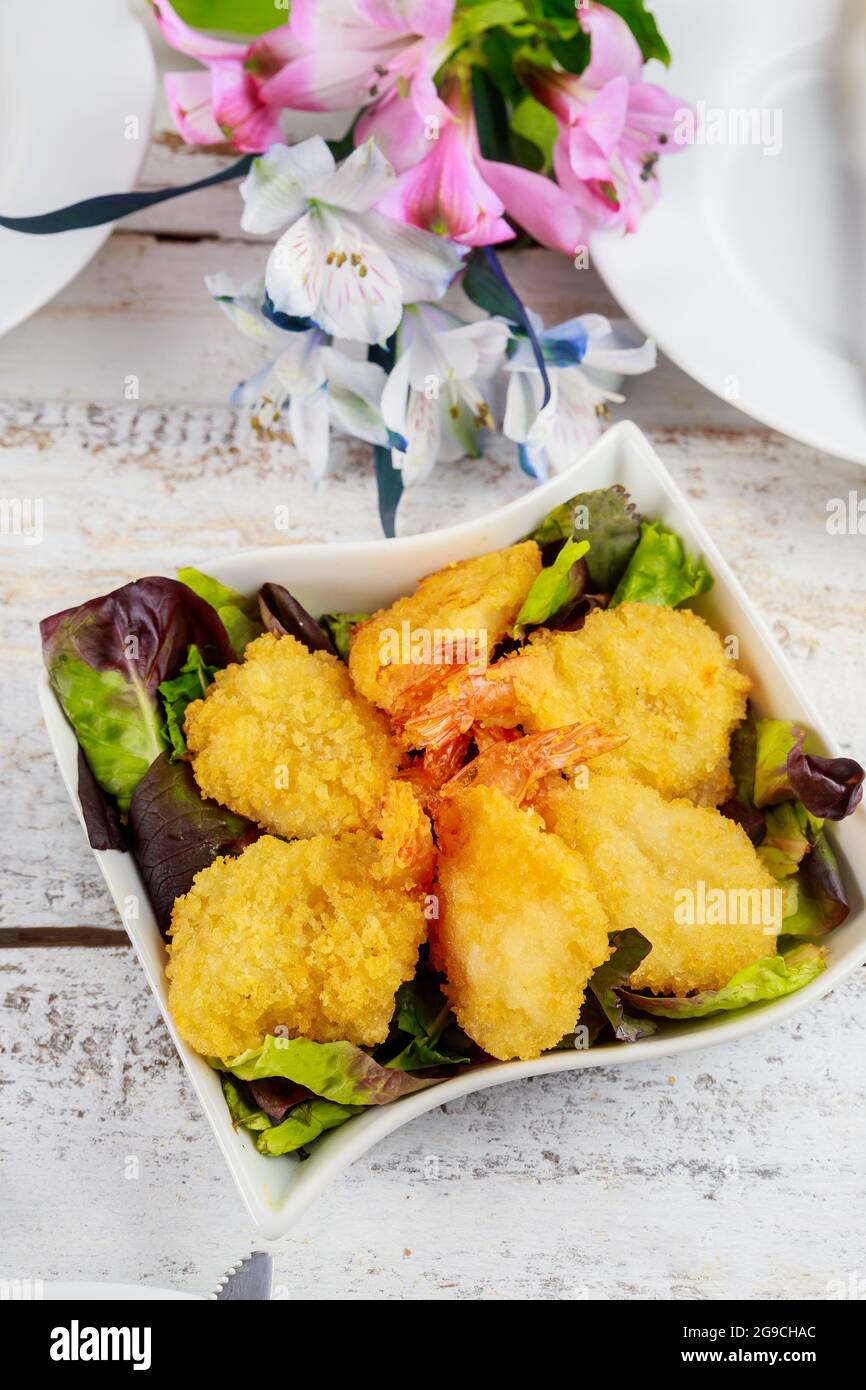 Frittierte panierte Garnelen mit grünem Salat und Tischset. Stockfoto