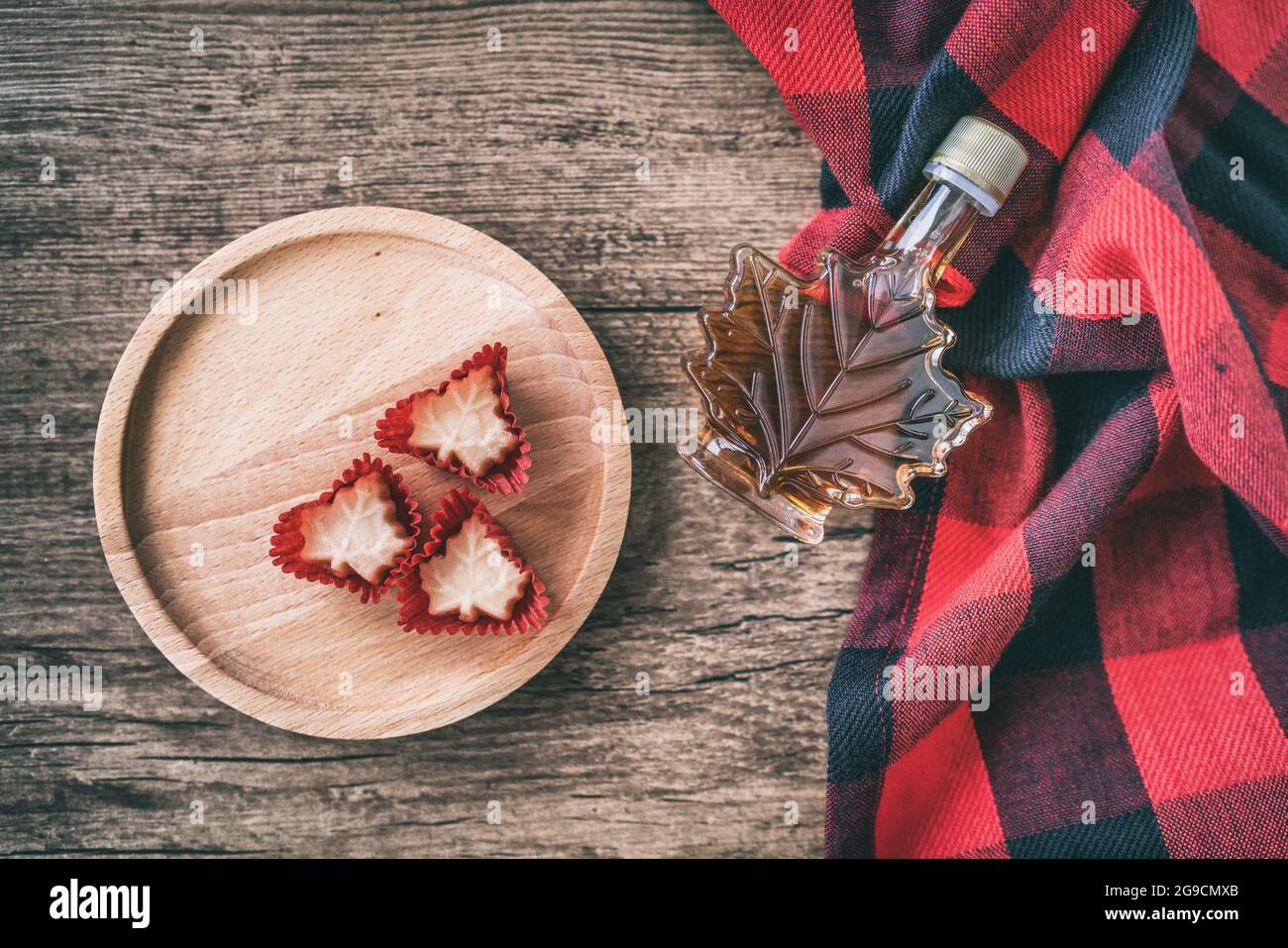 Ahornsirup Flasche aus Quebec mit Geschenk Süßigkeiten weichen Zucker Draufsicht auf rustikalem Holzhintergrund für Touristen Souvenir. Kanada Sorte EIN Bernstein süß Stockfoto