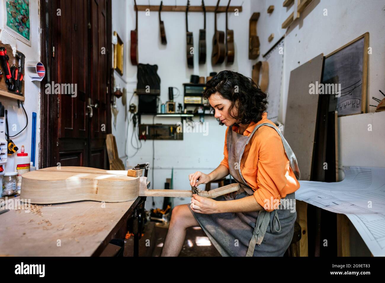 Eine Geigenbauerin, die in ihrer Musikinstrumentenwerkstatt Gitarren macht Stockfoto