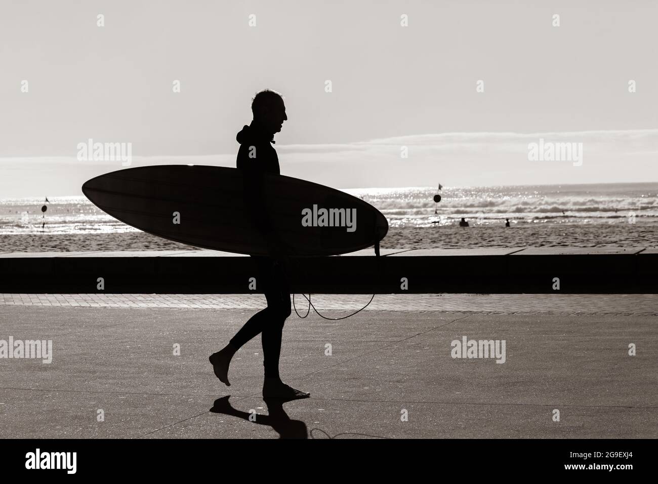 Die Silhouette des Surfers war an der Strandpromenade nicht zu erkennen und ging zum Surfen im Meer. Stockfoto