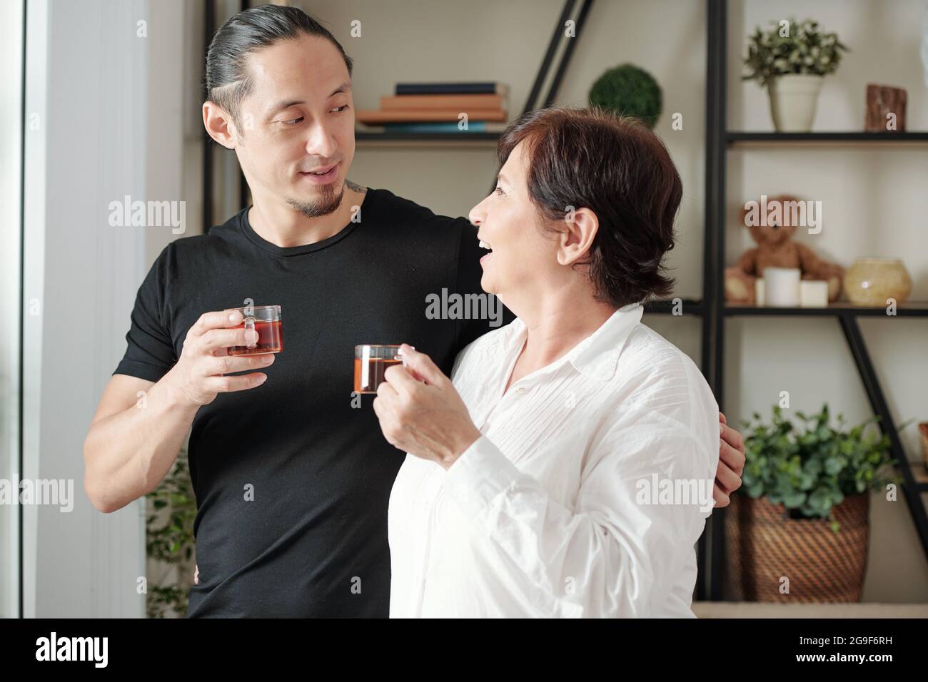 Älterer Sohn im Gespräch mit seiner Mutter, während sie gemeinsam im Zimmer Tee trinken Stockfoto