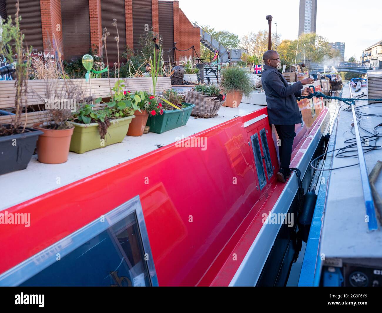 Ein schwarzer Mann auf einem schmalen Boot entlang des Regent’s Canal in Little Venice, London Stockfoto