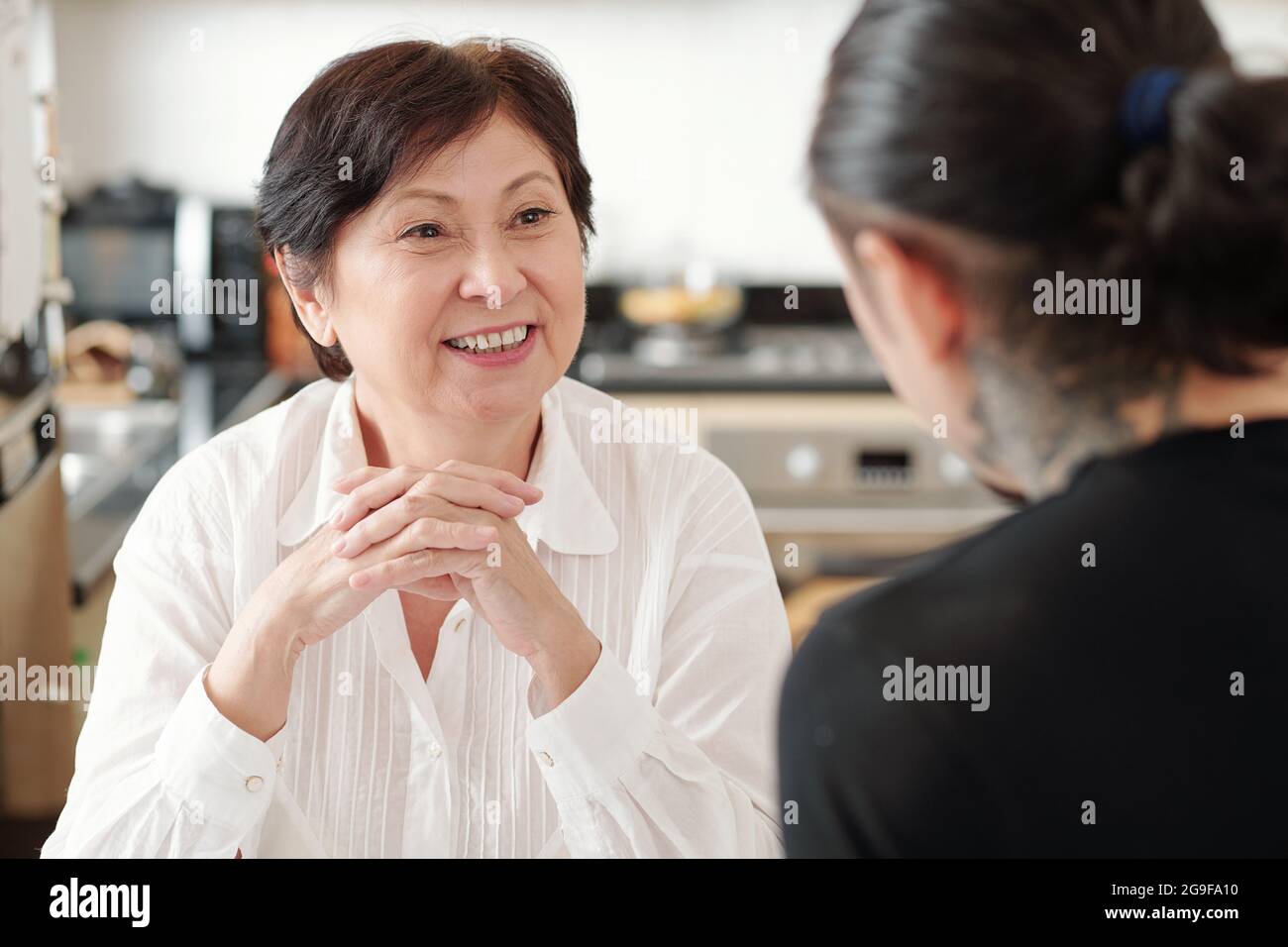 Asiatische reife Frau lächelt und genießt das Gespräch mit ihrem älteren Sohn zu Hause Stockfoto