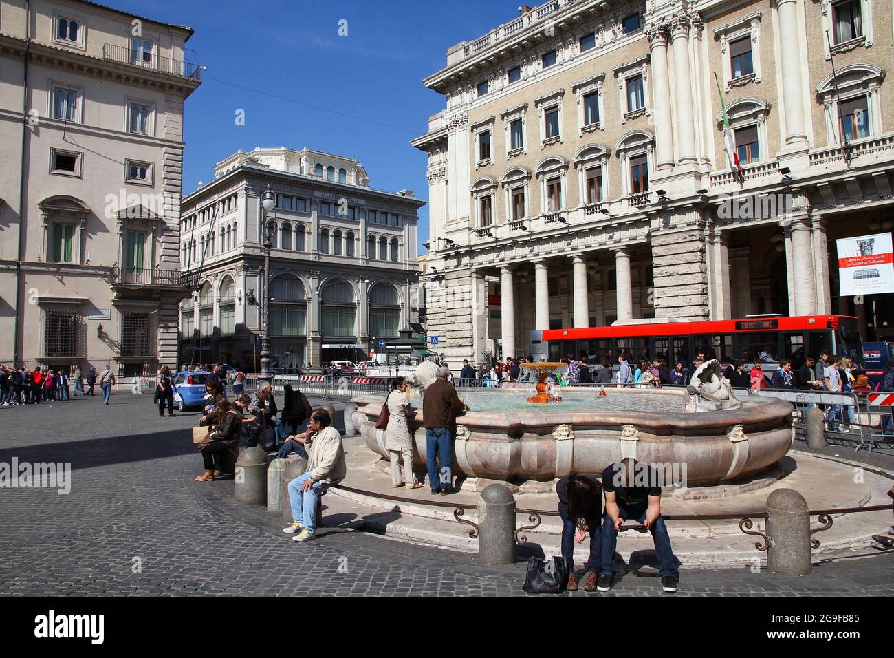 ROM, ITALIEN - 10. APRIL 2012: Am Brunnen auf dem Piazza Colonna in Rom sitzen Menschen. Nach offiziellen Angaben wurde Rom von 12.6 Millionen Menschen besucht Stockfoto