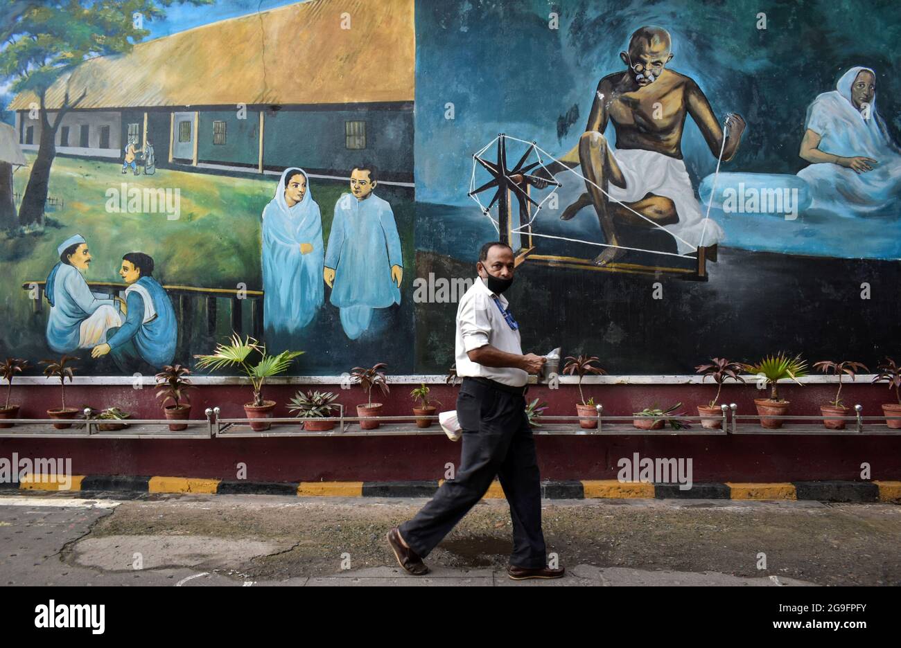 Kalkutta, Indien. Juli 2021. Ein Mann kommt neben einem Wandgemälde von Mahatma Gandhi vor einem Bahnhof in Kalkutta vorbei. (Foto: Sudipta das/Pacific Press/Sipa USA) Quelle: SIPA USA/Alamy Live News Stockfoto