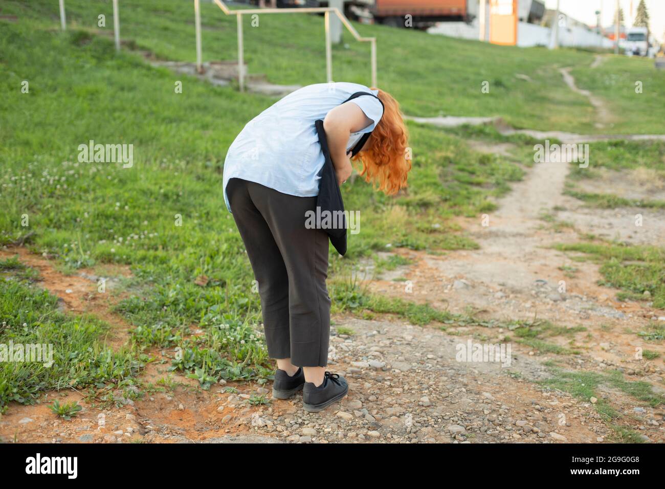 Das Mädchen beugte sich nieder, um etwas auf dem Boden zu sehen. Das Mädchen ließ eine kleine Sache fallen. Die Frau sucht Schmutz auf der Kleidung. Stockfoto