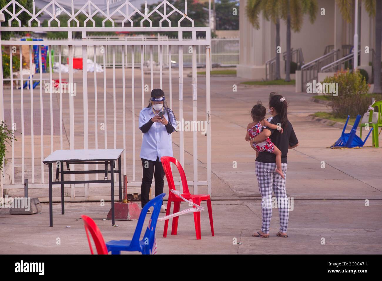 Phnom Penh, Kambodscha. 26. Juli 2021. Seit 5 Monaten kämpft Phnom Penh mit einem COVID - 19 Anstieg. Eine kambodschanische Krankenschwester sendet eine Nachricht auf ihrem Smartphone, während sie sich mit einer COVID-positiven Mutter und Tochter sozial distanziert, an einer Virusmassenteststelle. Kambodschaner, die positiv testen, können den Teststandort nicht verlassen und müssen einen Freund oder einen Verwandten anrufen, um ihre persönlichen Sachen für den Krankenhausaufenthalt abzuholen. Quelle: Kraig lieb / Alamy Live News Stockfoto