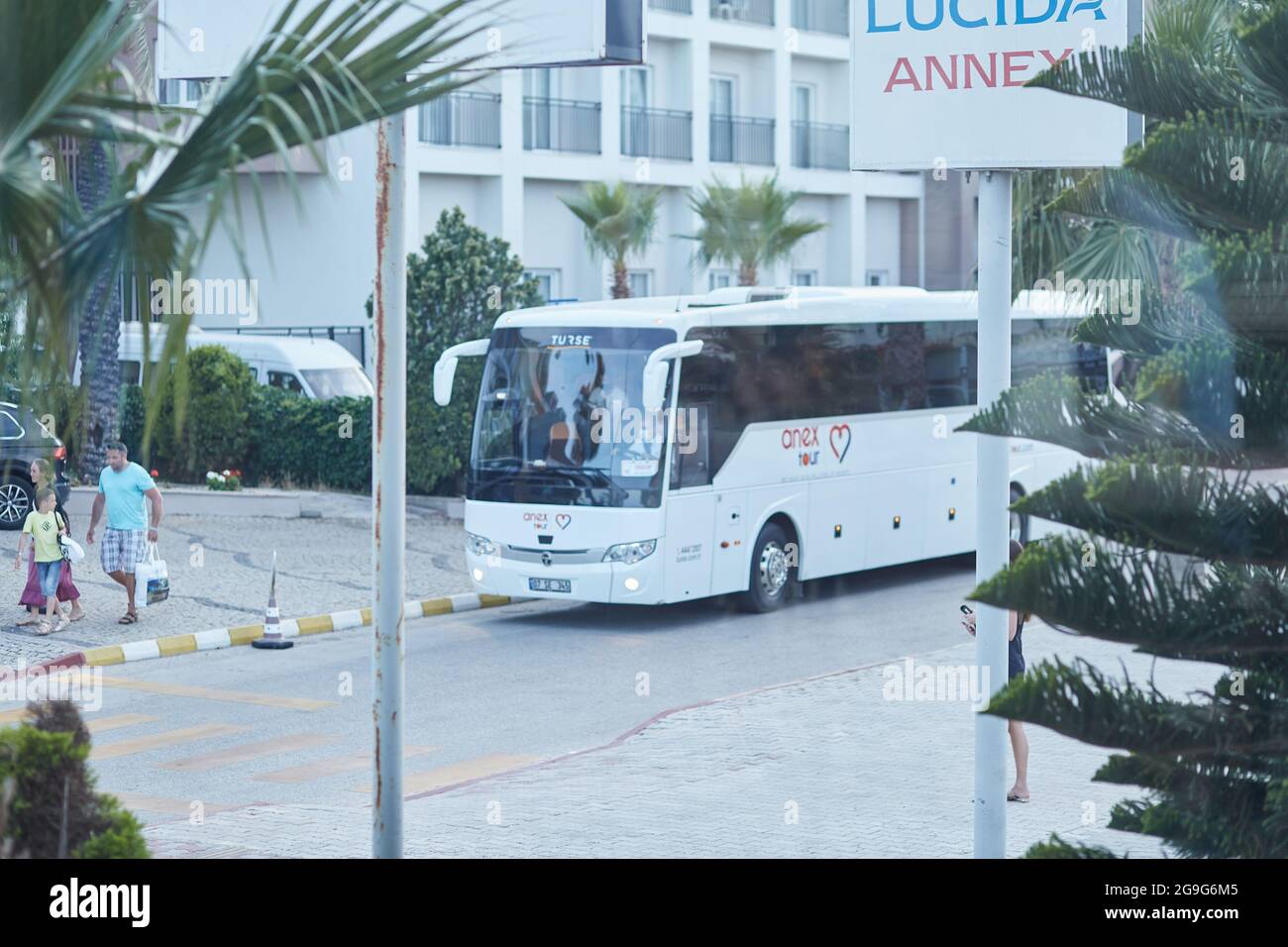 Kemer, Türkei - 23. Mai 2021: ANEX Tour Reisebus, Promenade mit blühenden Bäumen, Palmen, grüner Natur, Autos bei Sonnenuntergang. Redaktionelle Lifestyle-Ansicht. Hochwertige Fotos Stockfoto
