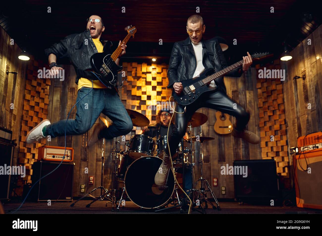 Zwei brutale Musiker springen mit E-Gitarren Stockfoto