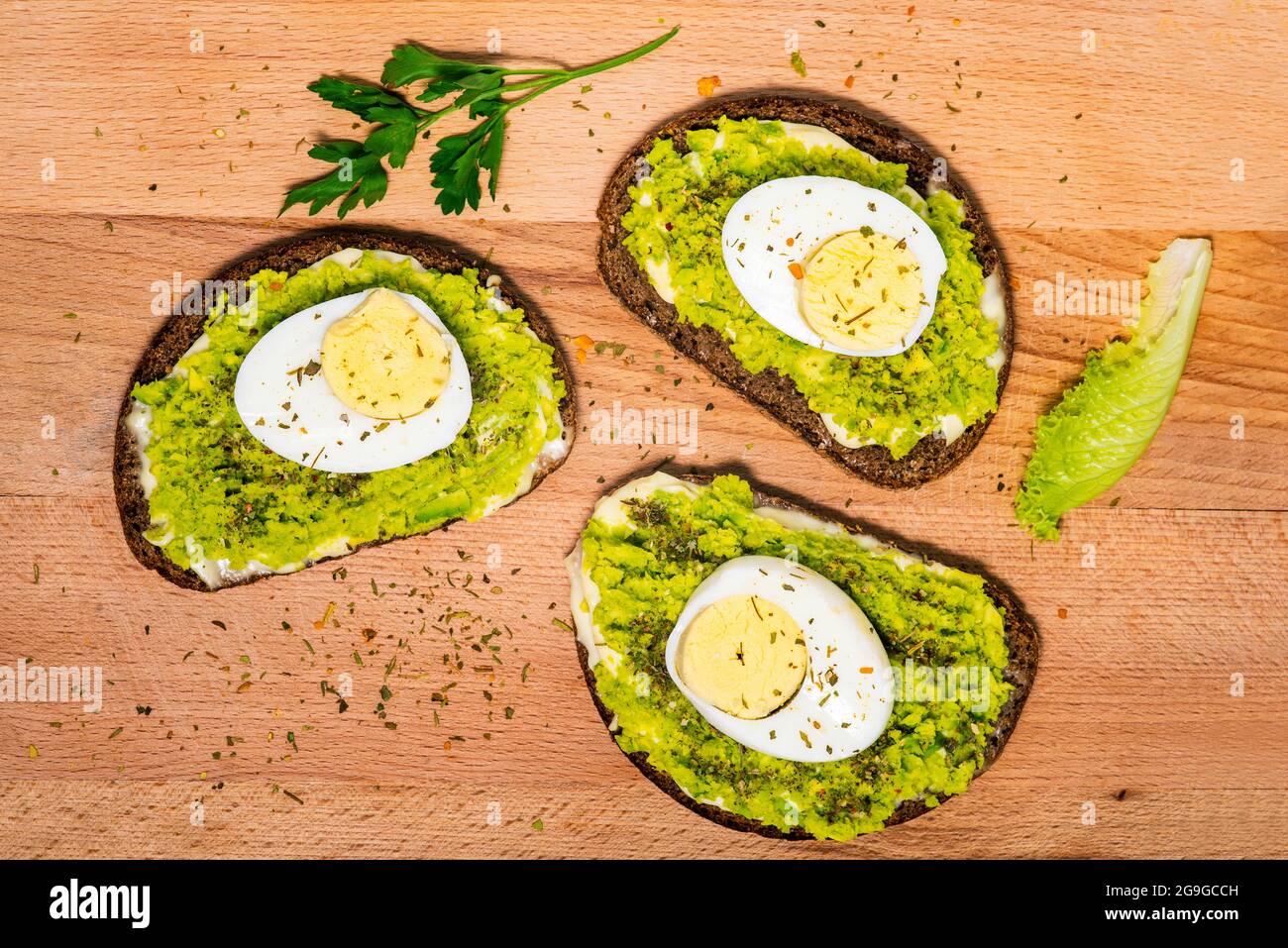 Sandwich mit Avocado und Ei auf Holzboden. Gesundes Essen, vegetarische Snacks. Draufsicht, flach liegend. Stockfoto