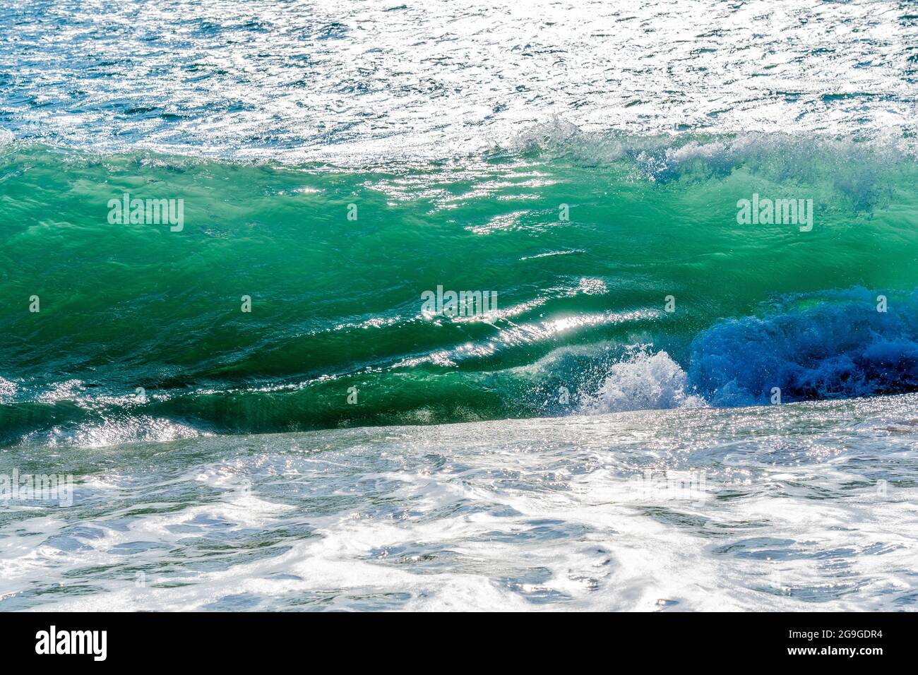 Sandige Küste mit einer schönen Spritzwelle. Schäumende weiße Welle an einem sauberen Sandstrand, selektiver Fokus. Natürliche Sommerfotos mit Kopierbereich. Blaue weiche Welle als Hintergrund. Hochwertige Fotos Stockfoto