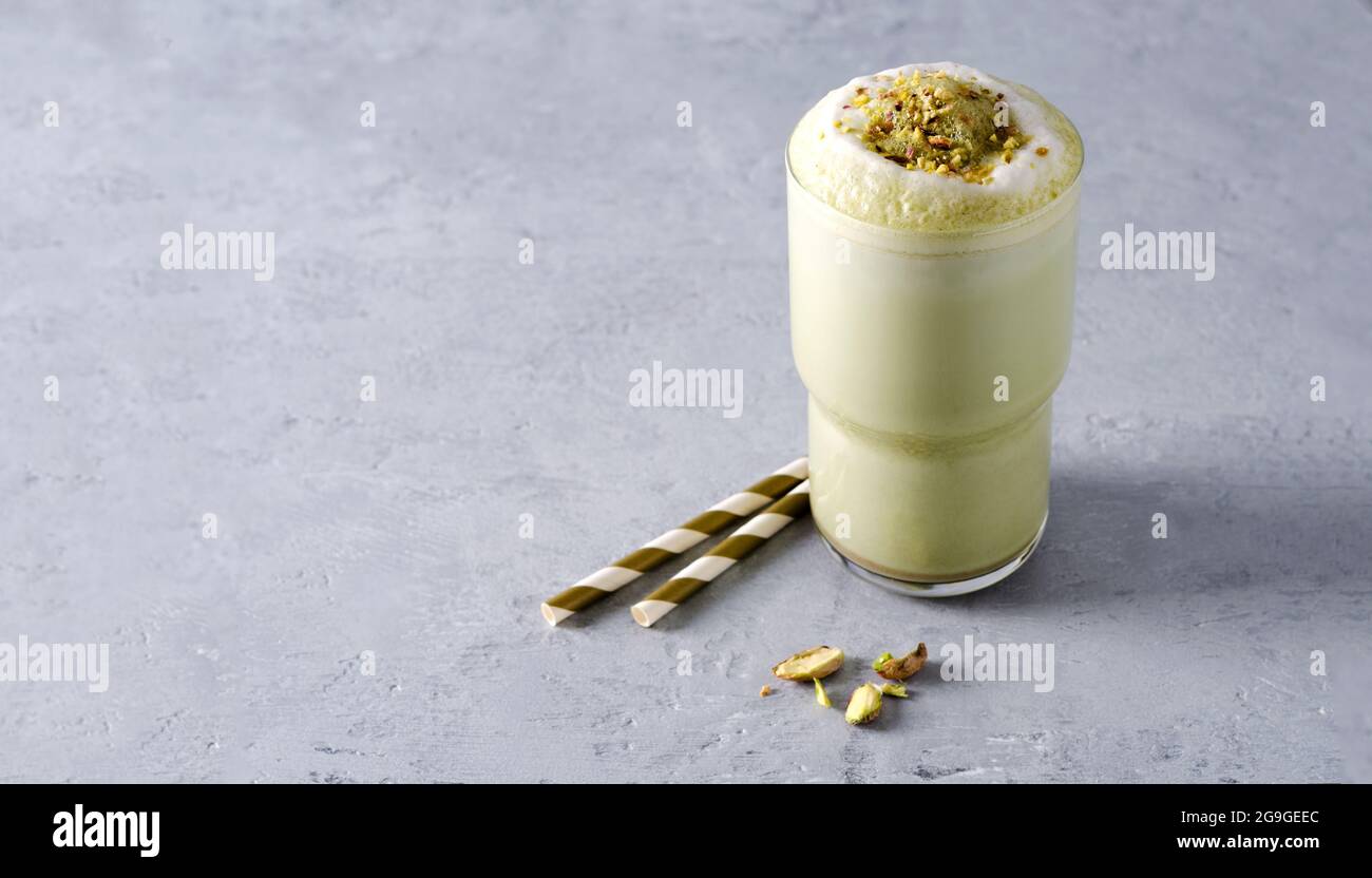 Grüner Tee Matcha Kaffee mit Schaum bestreut mit Nüssen auf einem grauen Beton Hintergrund mit Kopierraum Stockfoto