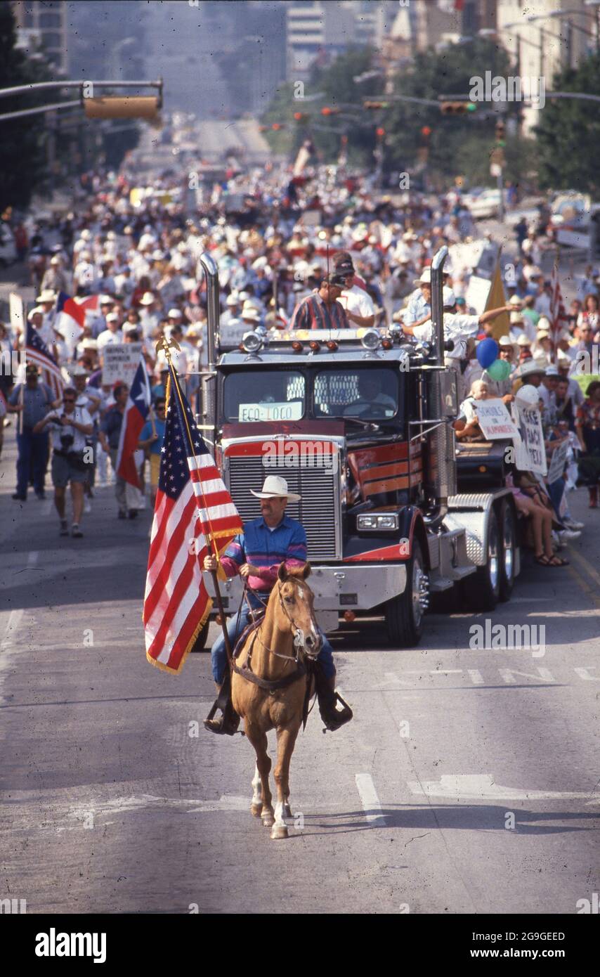 Austin Texas USA, 1993: Ein Mann auf dem Pferderücken, der eine texanische Flagge trägt, führt einen Protestierenden, der die Congress Avenue in Richtung Capitol aufmarschiert. Die Gruppe setzt sich für Steuerrechte für Privateigentum ein, die durch ein Gesetz in der aktuellen Sitzung der texanischen Legislative bedroht werden. ©Bob Daemmrich Stockfoto