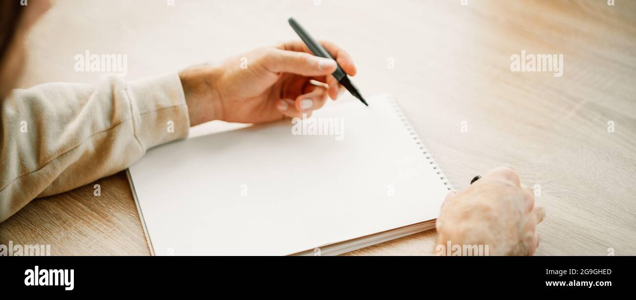 Banner eines Kakausers Hände Schreiben in einem leeren Papier Notizbuch mit einem Stift, Projektplanung, Erstellen einer Einkaufsliste. Notizblock mit Platz für Text Stockfoto