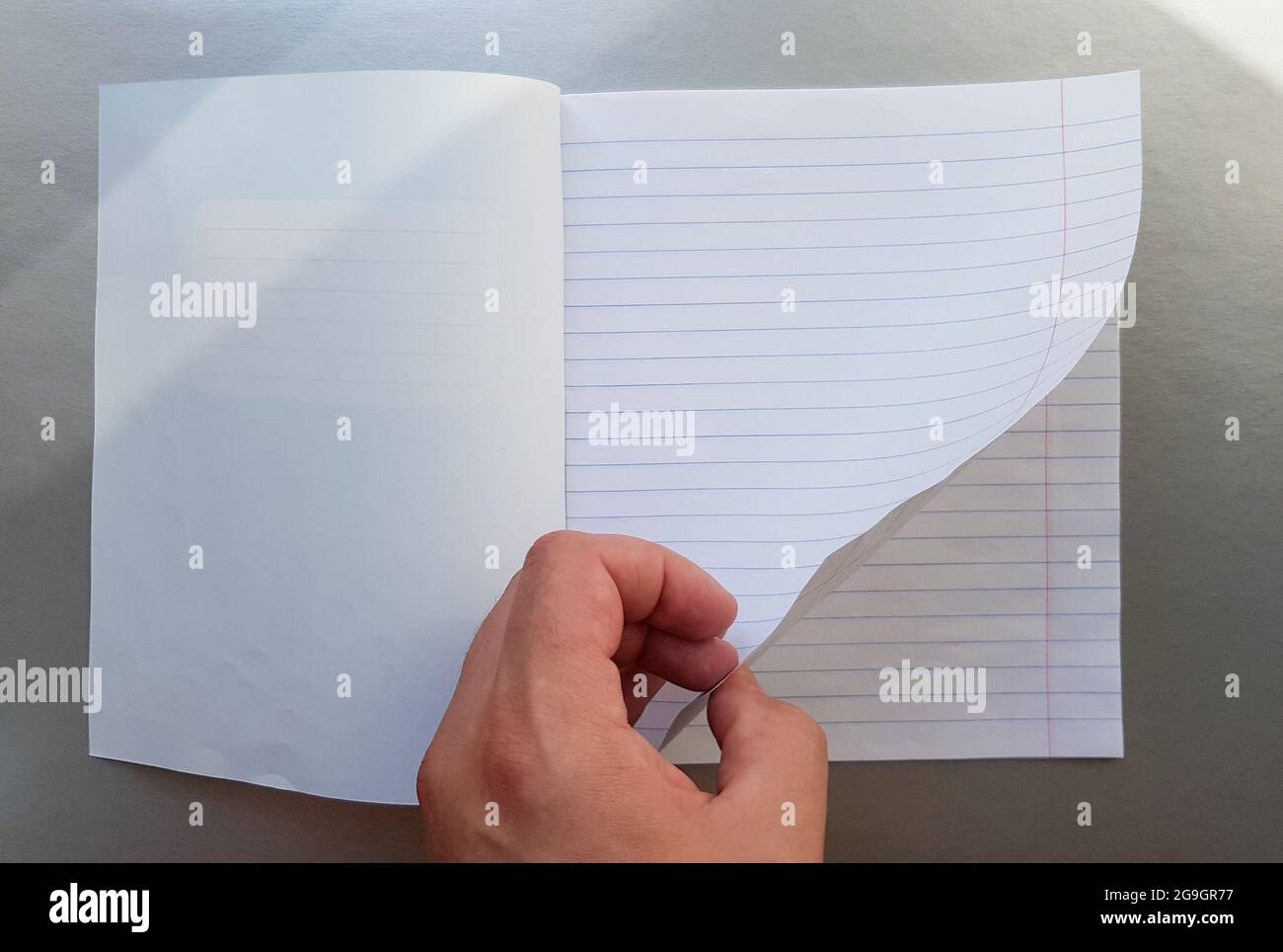 Designkonzept - Draufsicht einer hochwertigen männlichen Hand, die durch ein Blatt blau gestreiftes Notizbuch blättert. Draufsicht, Kopierbereich, flach liegend. Stockfoto