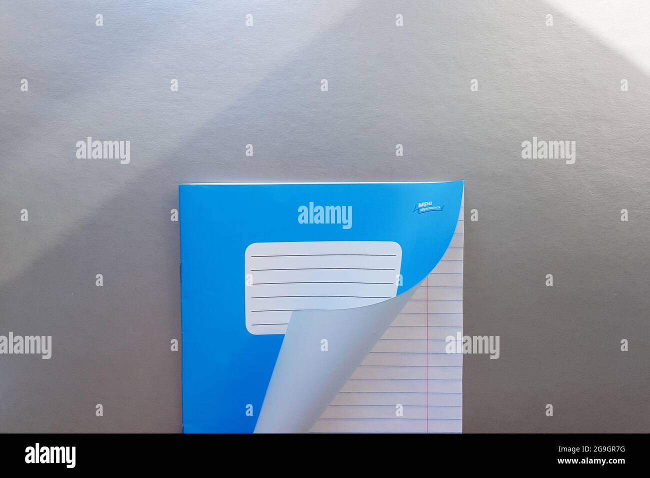 Designkonzept - Draufsicht einer hochwertigen männlichen Hand, die durch ein Blatt blau gestreiftes Notizbuch blättert. Draufsicht, Kopierbereich, flach liegend. Stockfoto