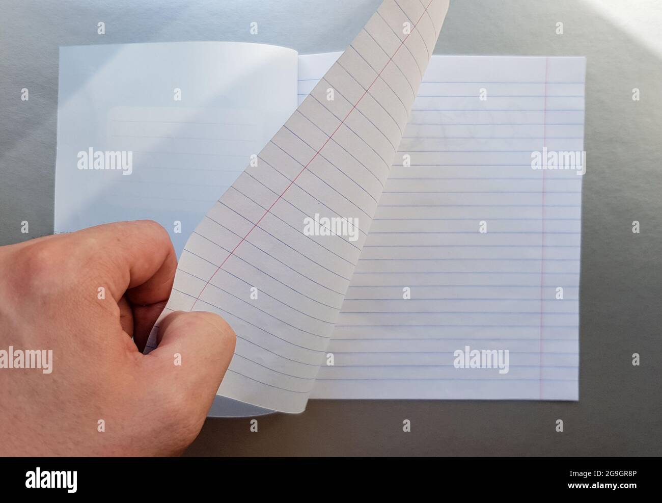 Designkonzept - Draufsicht einer hochwertigen männlichen Hand, die durch ein Blatt blau gestreiftes Notizbuch blättert. Draufsicht, Kopierbereich, flach liegend. Stockfoto