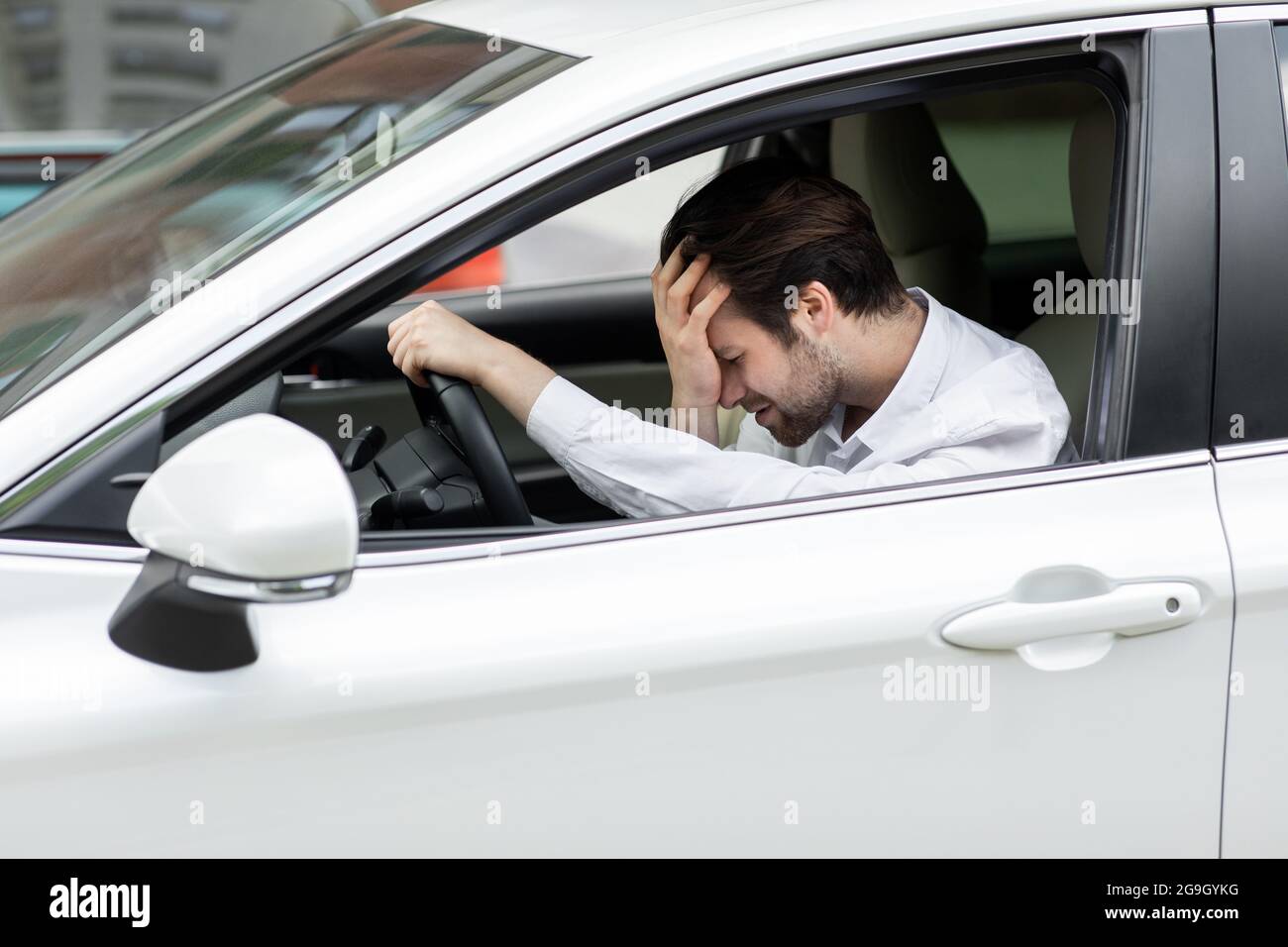 Geschäftsmann, der im eigenen Auto saß, steckte im Verkehr fest, hielt seine Hand auf der Stirn und wartete nervös. Unglücklich Millennial attraktiv traurig europäischen Mann in Stockfoto