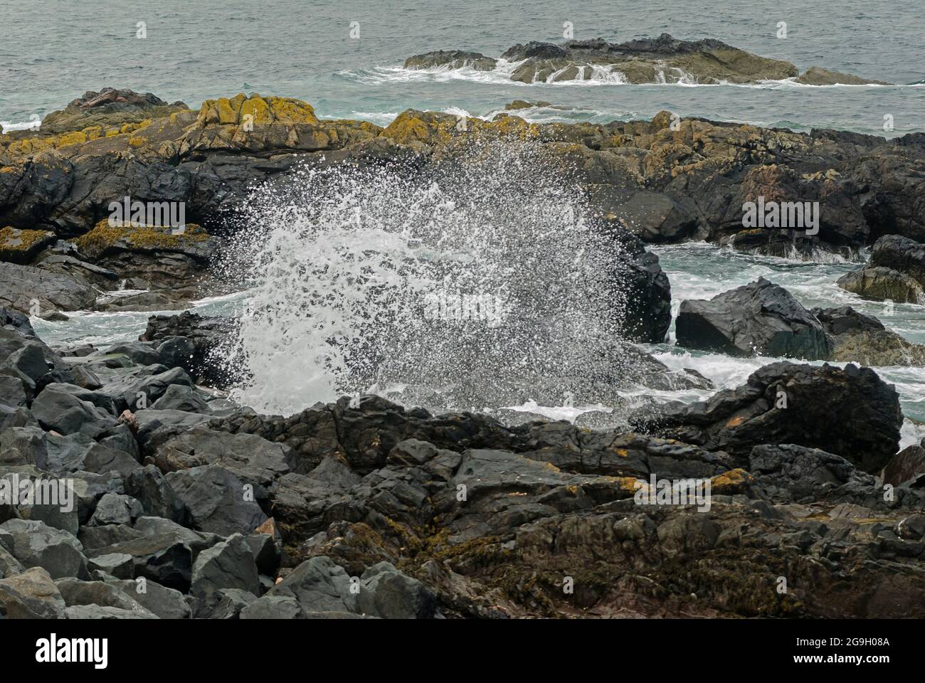 Wellen und Sprühnebel, die gegen Felsen krachen Stockfoto