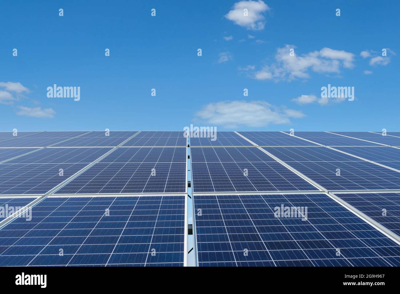 Reihe von Sonnenkollektoren auf einem Solarpark unter blauem Himmel. Stockfoto