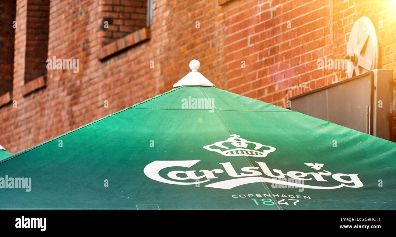 Carlsberg-Schriftzug und Logo der dänischen Brauerei auf einem grünen Sonnenschirm vor einer Backsteinfassade in Hamburg, 22. Juli 2021 Stockfoto